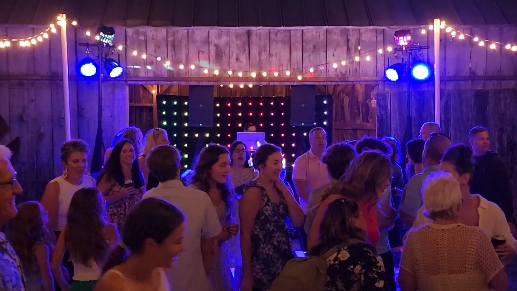 Guests dancing in a barn venue under string lights